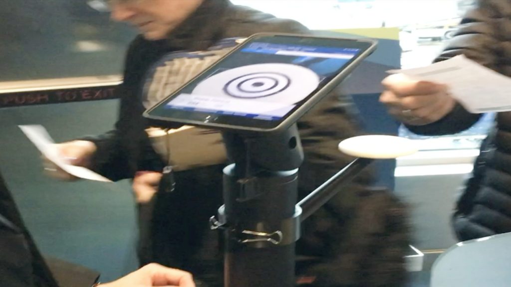 A passenger scans their own boarding pass against the target on the iPad stand at the gate.